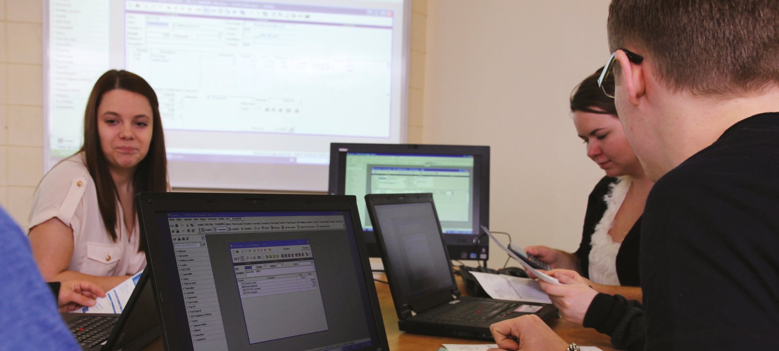 Étudiants en table ronde travaillant sur des portables en équipe